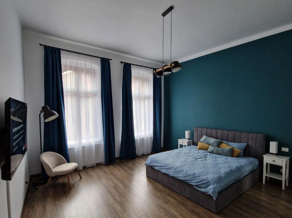 a bedroom with blue walls and a bed and a chair at HiRooms Brașov in Braşov