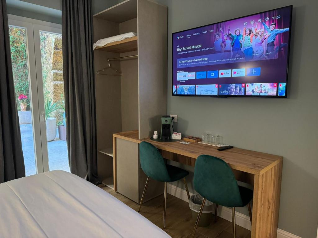 a bedroom with a desk with two chairs and a tv on the wall at Krysos Luxury Rooms in Agrigento