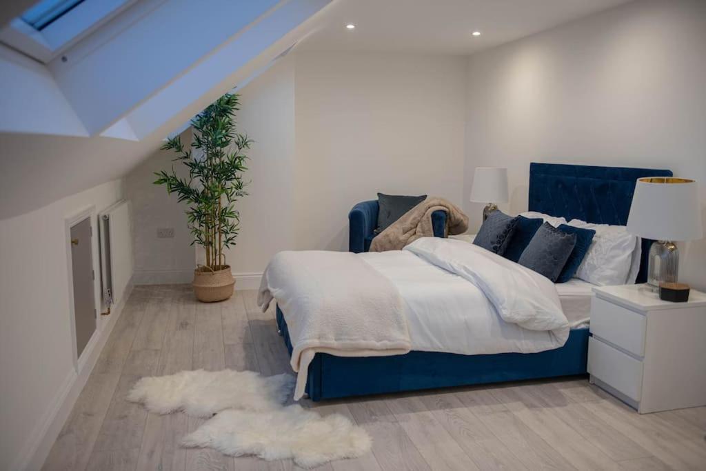 a bedroom with a blue bed with pillows at Stylish Skylight Room in a Luxury House in Catford