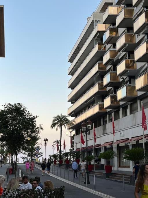 un grand bâtiment avec des personnes debout devant lui dans l'établissement Petit 2 pièces Carré d'Or, à Nice