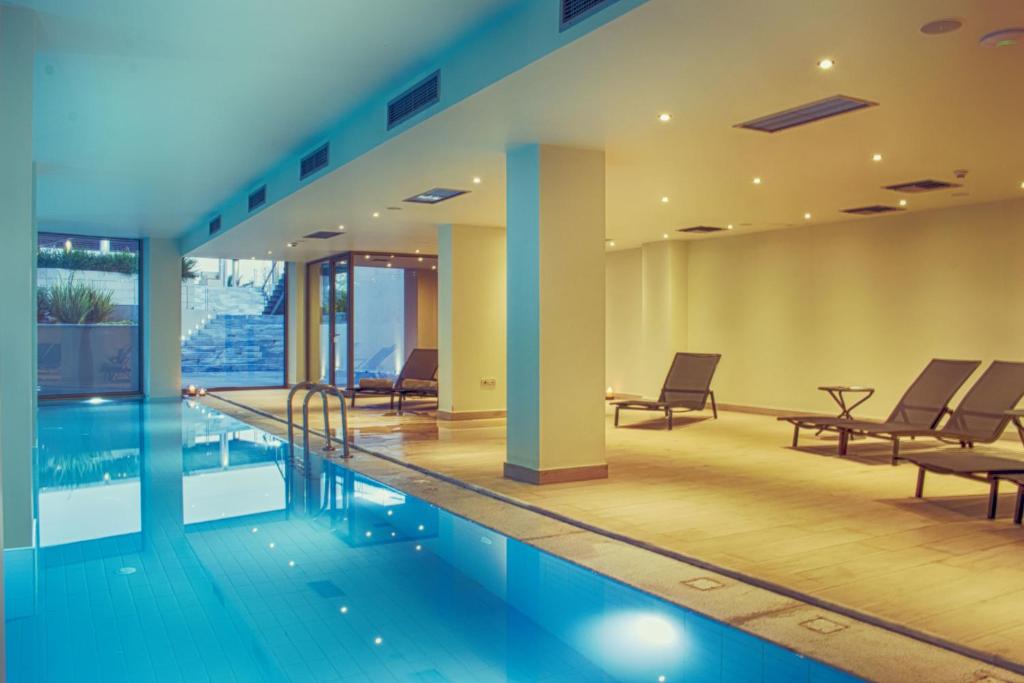 a swimming pool with chairs and a table in a building at Horizon Blu Boutique Hotel in Kalamata