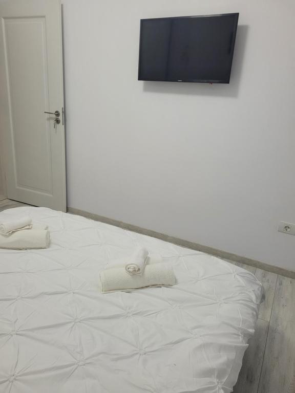 a white bed with two towels on top of it at Gold Tag Apartament in Timişoara