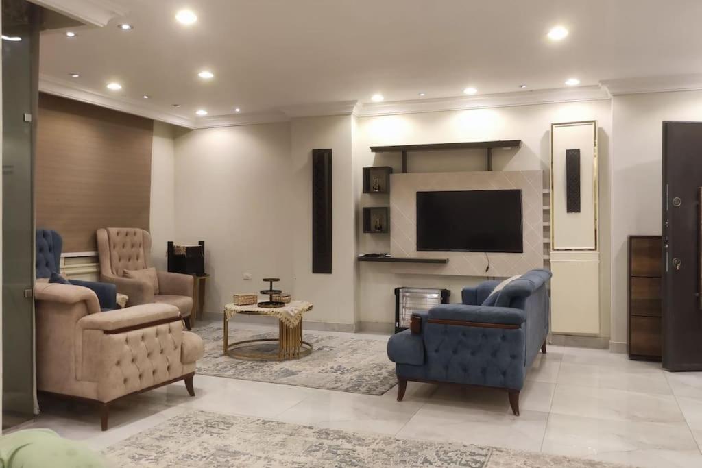 a living room with a tv and a couch and chairs at Comfortable softness in Cairo