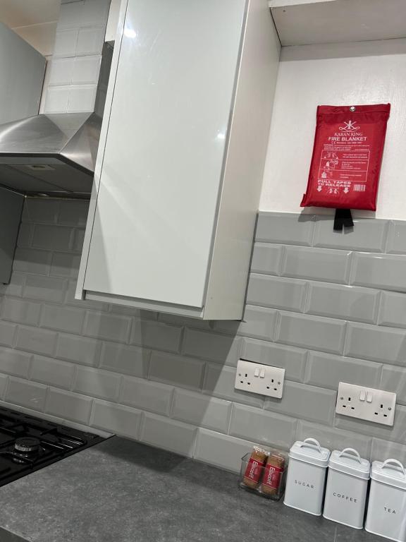 a kitchen with a red sign on the wall at Cosy 3 bedroom Near Heathrow - 6 beds, sleeps 7, FREE PARKING in Staines upon Thames