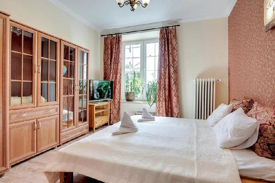 a bedroom with a large white bed and a television at Old Town Heart of Neptune in Gdańsk