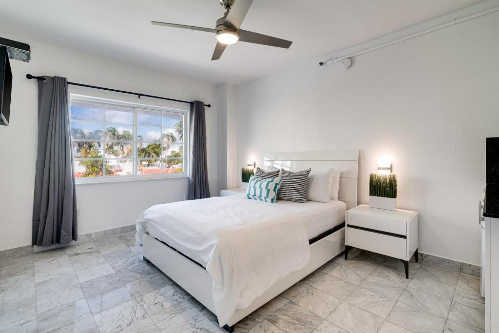 Un dormitorio blanco con una cama grande y una ventana en Best location in SOBE - 2 min to beach & Ocean Dr en Miami Beach