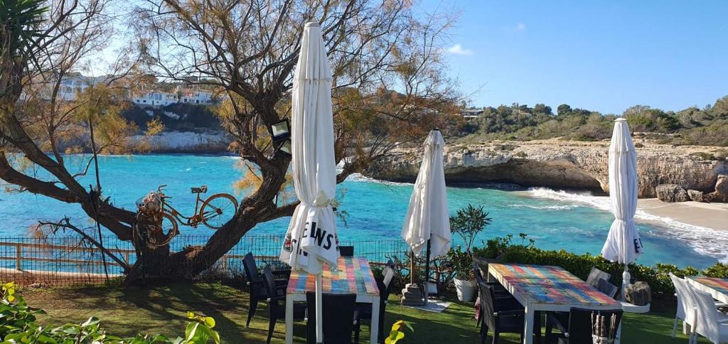 a table with white umbrellas next to the water at Casa Domingos Cales De Mallorca in Calas de Mallorca
