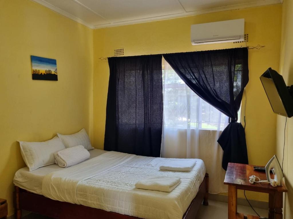 um pequeno quarto com uma cama e uma janela em Town Centre Apartment em Livingstone