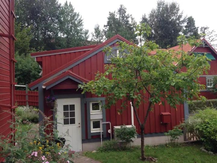 a red house with a white door and a tree at Lilla Gäststugan in Uppsala