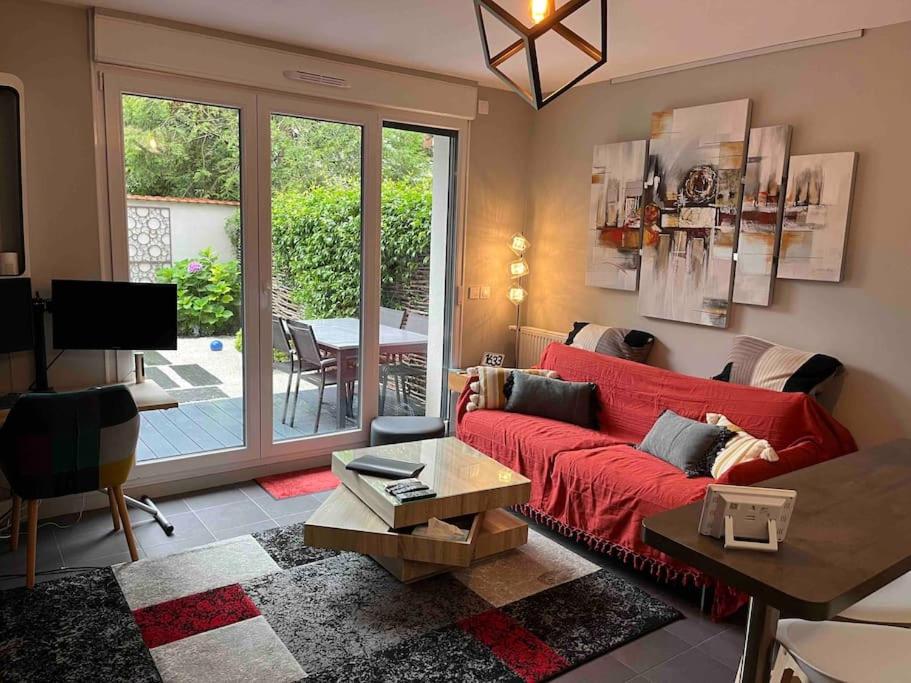 un salon avec un canapé rouge et une table dans l'établissement Coin de détente au centre ville, à Bondy