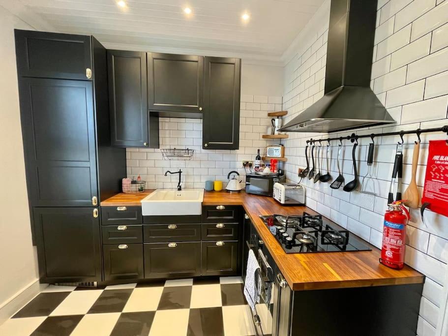eine Küche mit schwarzen Schränken und einem karierten Boden in der Unterkunft Stylish, Modern & refurbished flat, 1.5m beach in Southend-on-Sea