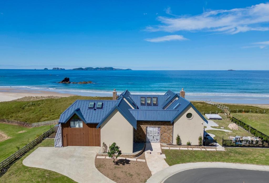 an aerial view of a house with the ocean in the background at Beachfront Paradise - Opito Bay Holiday Home in Opito Bay