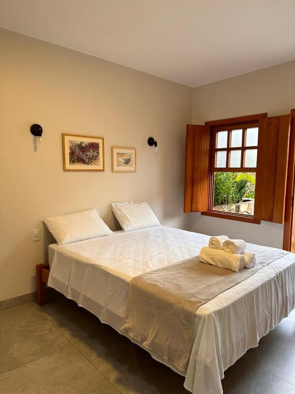 a bedroom with a bed with two towels on it at Pousada Mãe Natureza in Pirenópolis