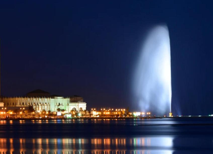 a water fountain in front of a city at night at غرفه وحمام مشترك داخل شقه مشتركه Single room and sharedللرجال فقط bathroom 1 Jeddah Corniche in Jeddah