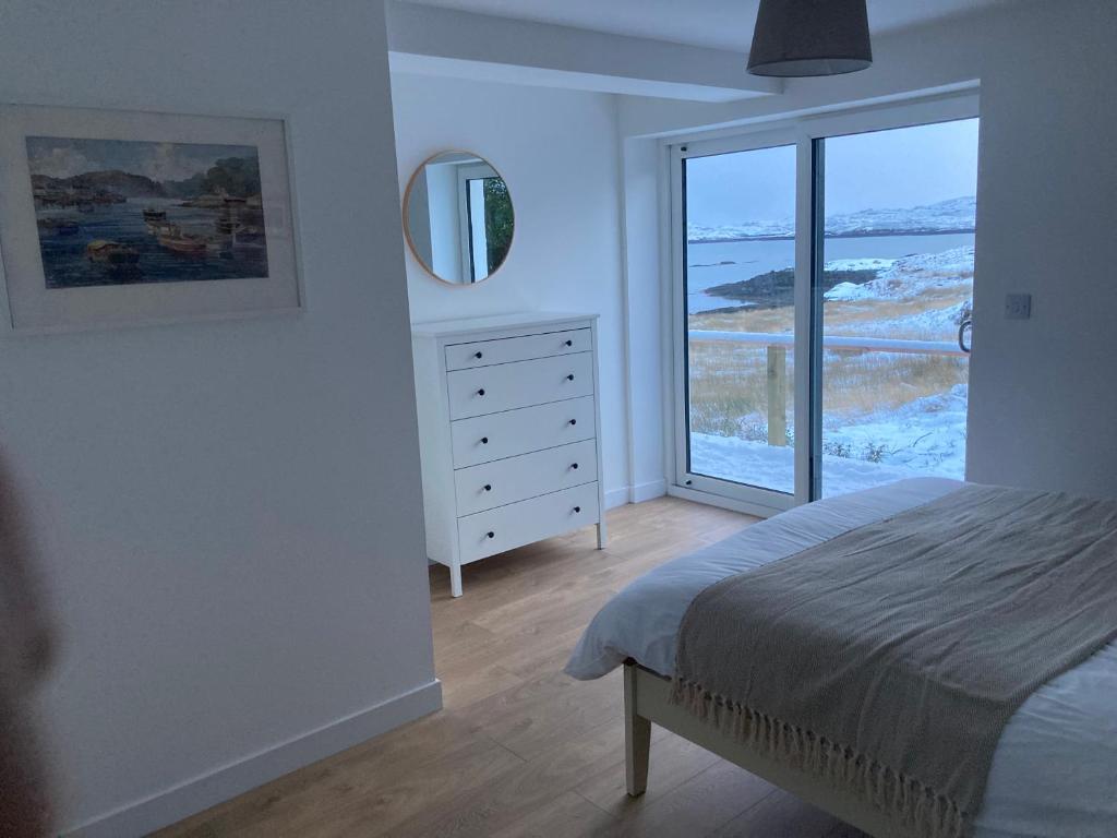 a bedroom with a bed and a large window at Urgha Bay in Tarbert