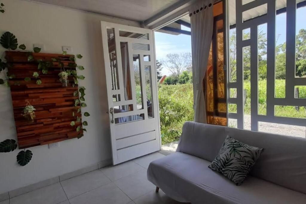 een woonkamer met een bank en een deur bij apartamento tranquilo rodeado de zonas verdes in Acacías