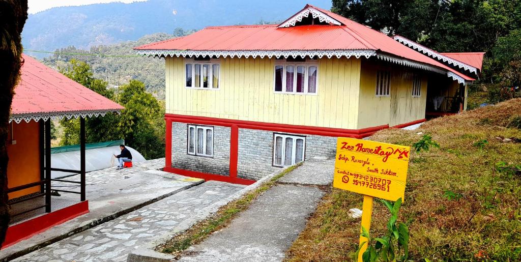 a small house with a red roof and a sign at Zen homestay in Ravangla