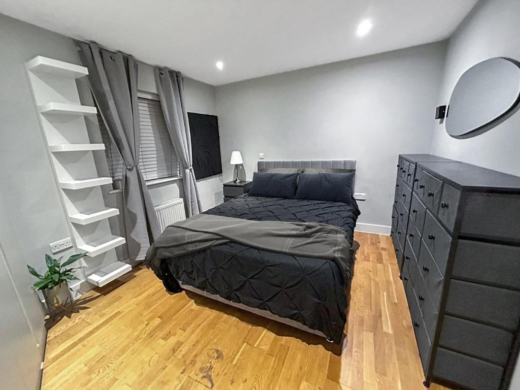 sypialnia z łóżkiem, komodą i lustrem w obiekcie Luxury 1 bedroom Apartment in London overseeing Canary Wharf with free parking w Londynie