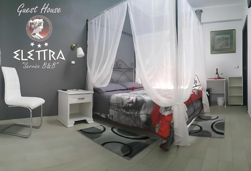 シラクーサにあるGuest House Elettraのベッドルーム1室(カーテン付きのベッド1台、椅子付)