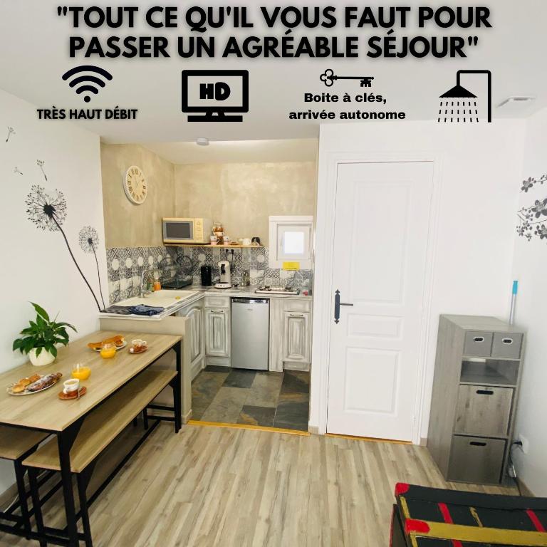 a kitchen with white cabinets and a table in a room at Studio centre village Soligny la Trappe proche Mortagne au perche in Soligny-la-Trappe