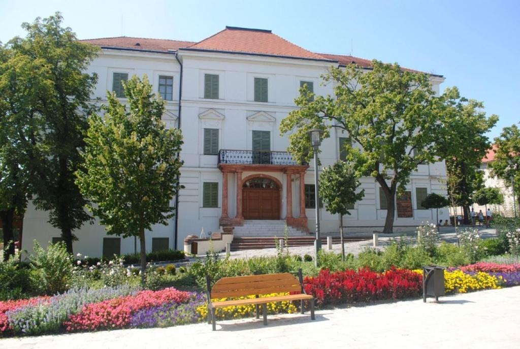 a white building with flowers and a bench in front at SEA-DWELLER APARTMENT in Balatonfüred