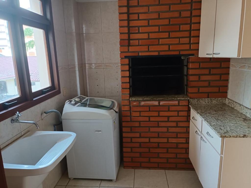 a bathroom with a brick wall and a washer and dryer at Apto grande em Camobi in Santa Maria
