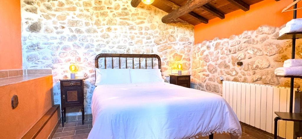 een slaapkamer met een bed en een stenen muur bij La Caseta in Arnés