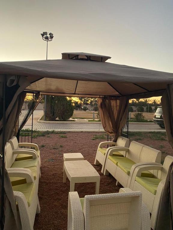 a gazebo with white chairs and tables under it at منتجع وِلف in Al Qā‘id
