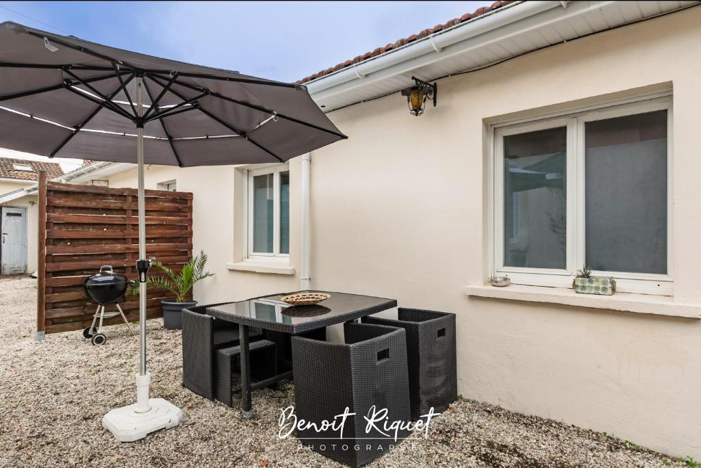 a black table with an umbrella in front of a house at Maisonnette Jardin Merignac in Mérignac