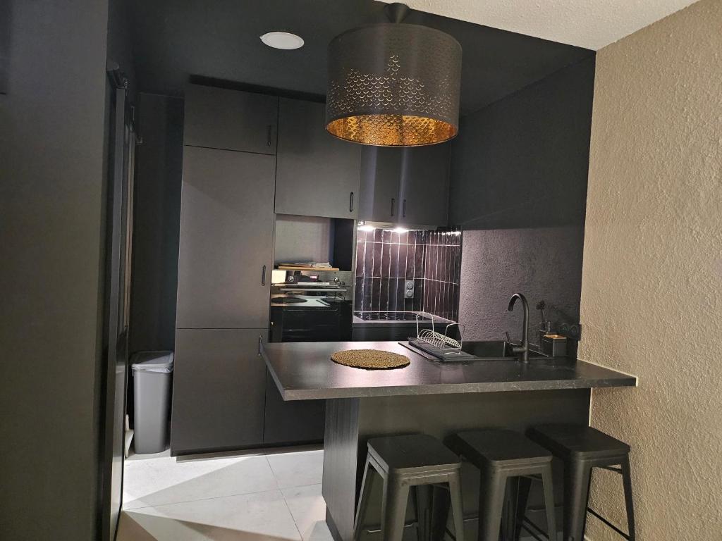 een keuken met zwarte kasten en een aanrecht met krukken bij le salon in Sablons