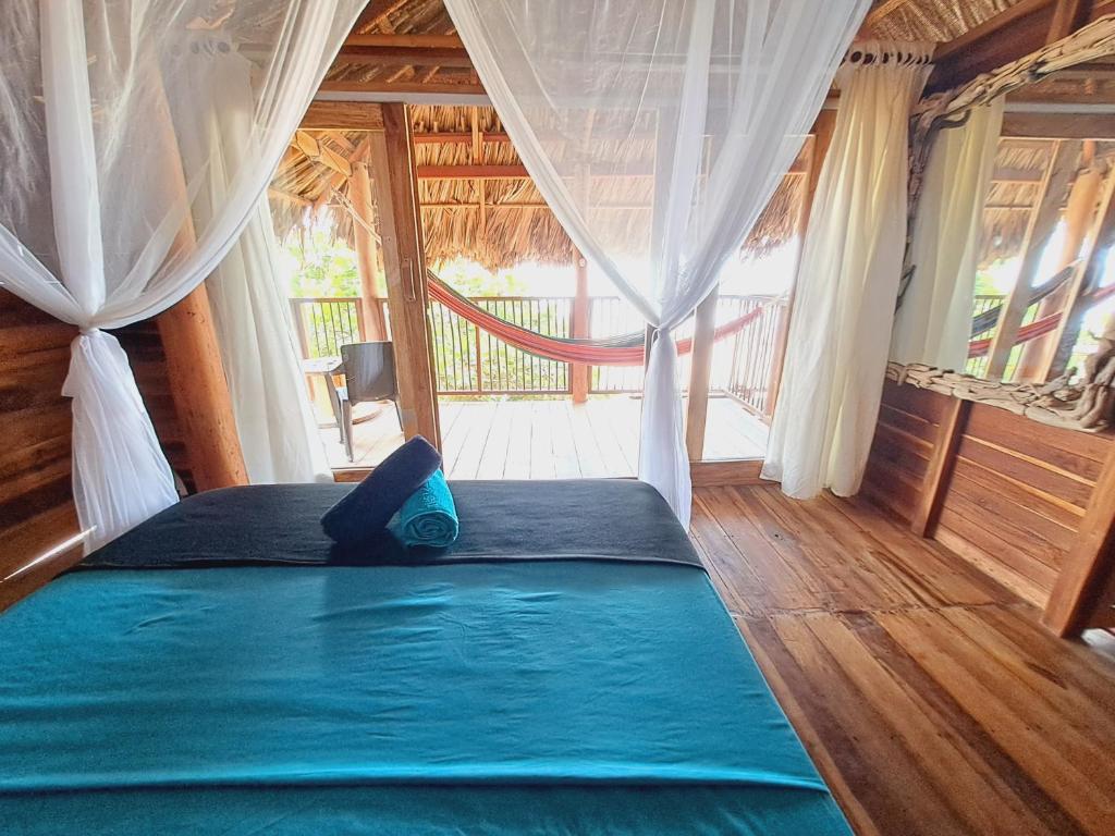 a bedroom with a bed with blue sheets and a window at Coco Lodge, vista al mar in La Poza