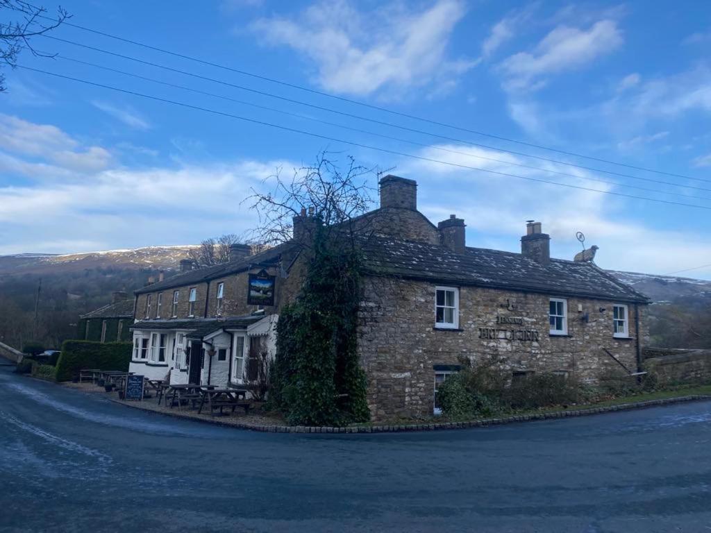 una vecchia casa di mattoni sul lato di una strada di The Bridge Inn a Reeth