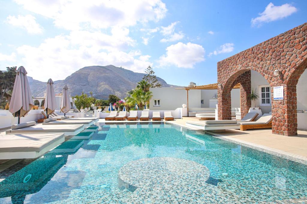 a pool with chairs and umbrellas next to a building at Dimitris Villa in Kamari