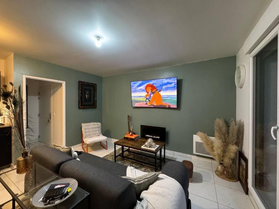 un salon avec un canapé et une télévision dans l'établissement Résidence Les Jardins d'Eugénie Near Disneyland, à Ferrières-en-Brie