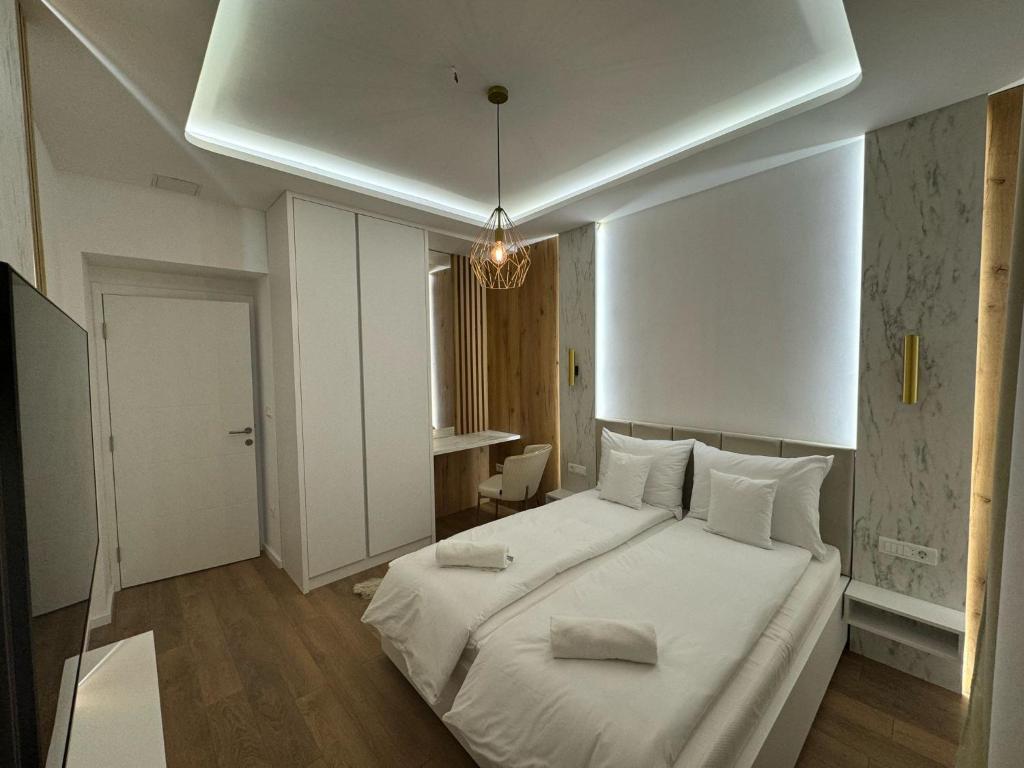 una camera da letto con un grande letto bianco con cuscini sopra di Mona Luxury Apartments - Free Garage Parking a Sarajevo