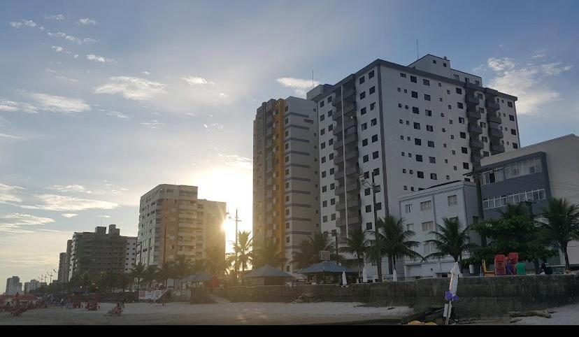 un grupo de edificios altos en una playa con la puesta de sol en Apartamento beira mar Centro da cidade WiFi grátis, en Mongaguá