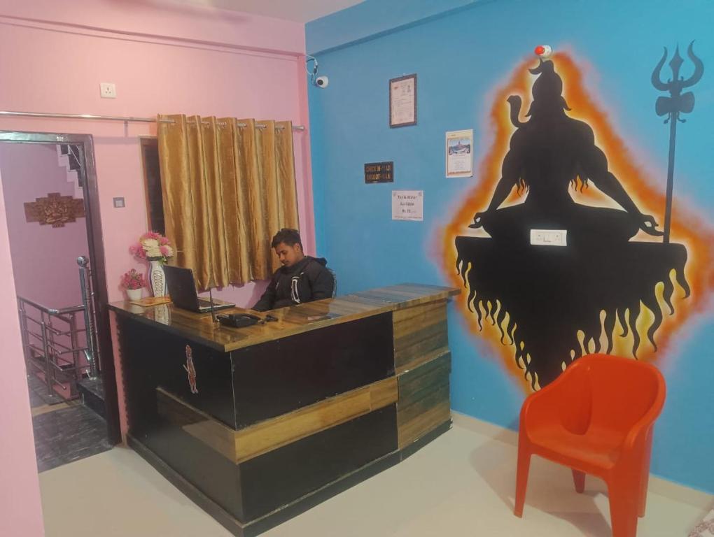 a man sitting at a desk with a laptop at Shiv Niketan Guest House 200mtr from Shri Ram mandir in Ayodhya