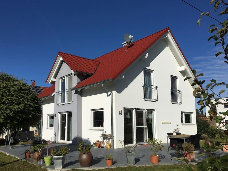 uma casa branca com um telhado vermelho em Schönes Familienhaus mit Herz im Grünen (Tübingen) em Kusterdingen