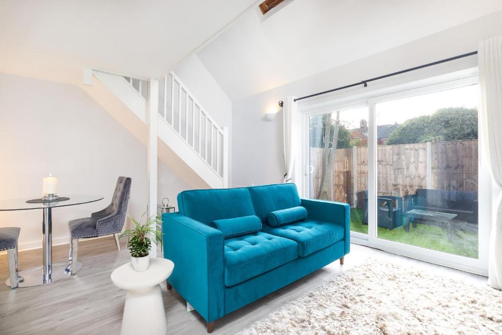 a living room with a blue couch and a table at Stylish Retreat in Nuneaton Centre with Sofa Bed, Garden and Super Fast Wi-Fi in Nuneaton