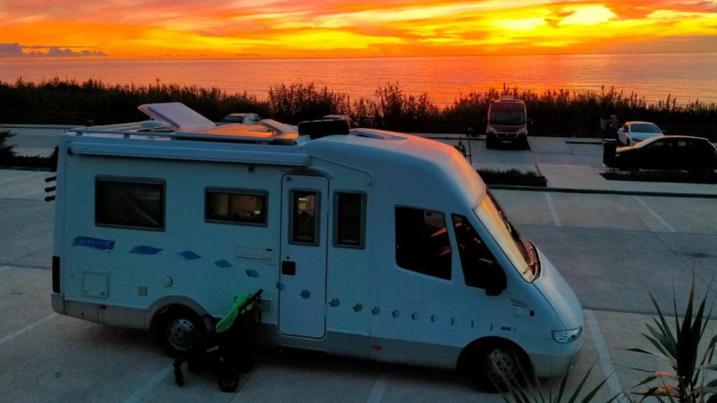 a camper van parked in a parking lot with a sunset at Autocaravana Lisboa in Frielas