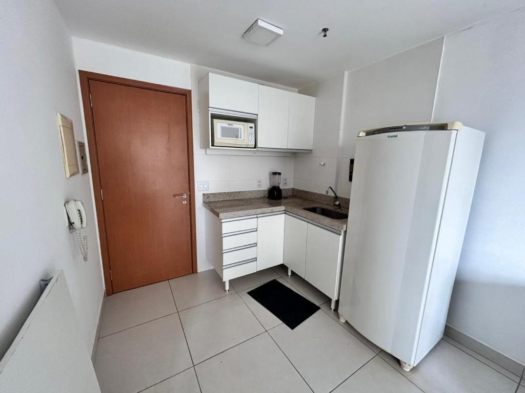 a kitchen with a white refrigerator and a brown door at 902. Flat Blend - Proibido fumar in Brasilia