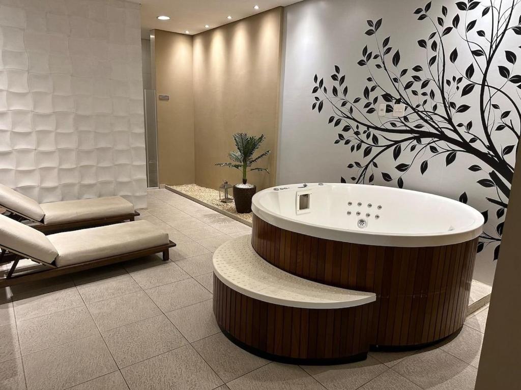 baño con bañera profunda, sofá y silla en Lindo ap garden Soul Paulista 102, en São Paulo