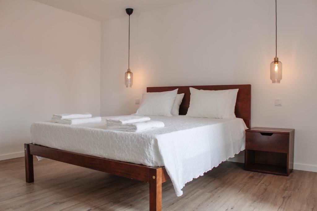 1 dormitorio con 1 cama con sábanas y almohadas blancas en Casa na Aldeia 1º Andar, en Arcos de Valdevez