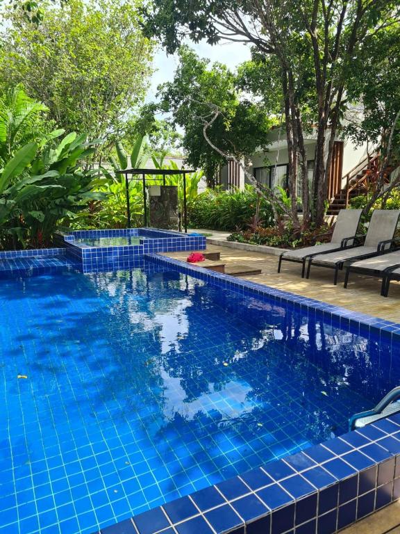a blue tile swimming pool with chairs and trees at Brisas do Sul Condo Boutique in Pipa