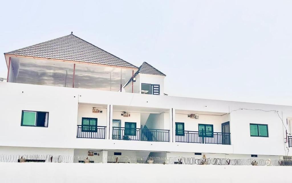 un edificio bianco con porte verdi e balcone di Ej guest house a Banjul