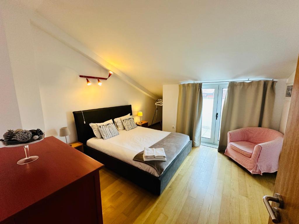 1 dormitorio con 1 cama y 1 silla rosa en Casas e Quintas de Praia, en Praia da Barra
