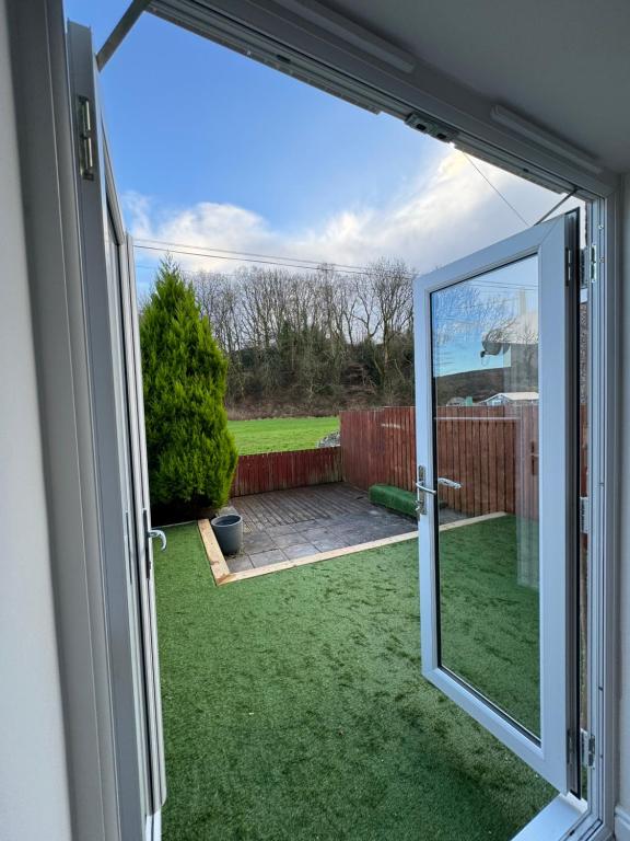 an open sliding glass door with a view of a yard at Spacious home near park and playing fields in Aberdare