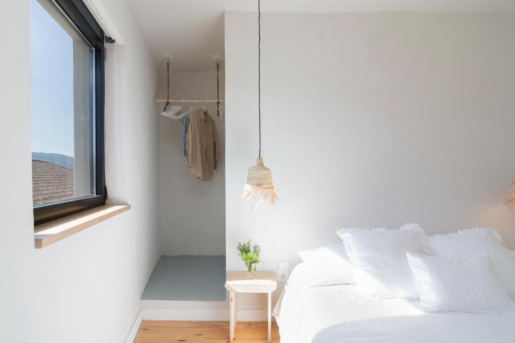 a white bedroom with a bed and a window at Casa da Zanjas in Seia