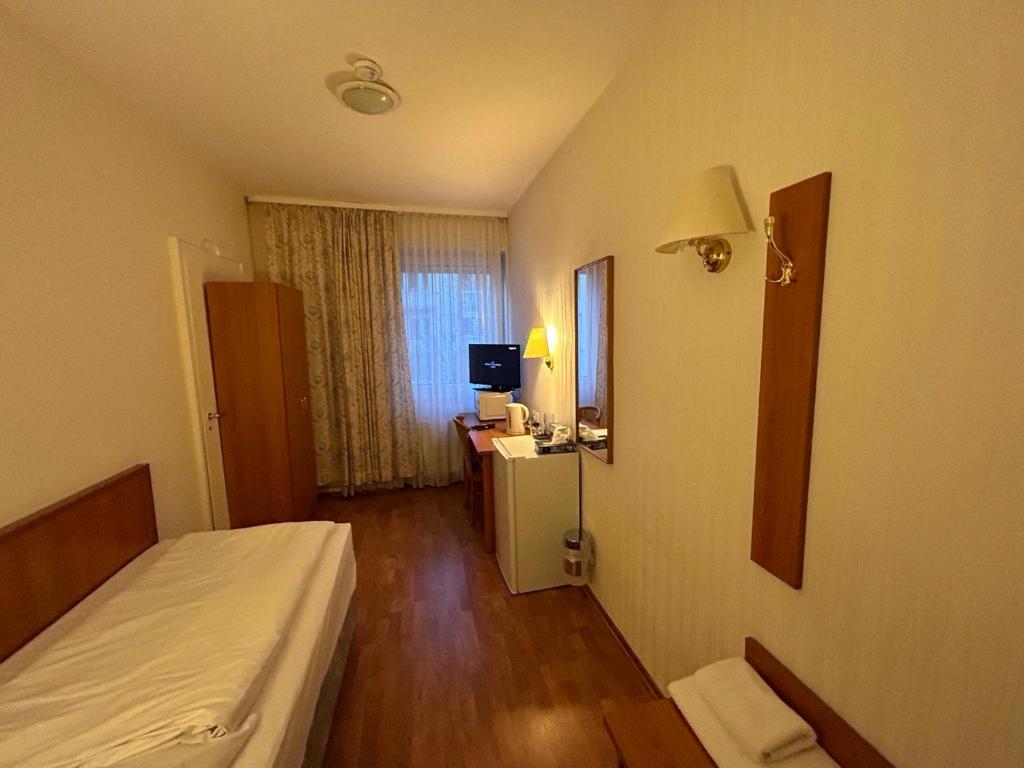 a bedroom with a bed and a desk with a television at WestEnd#202 in Frankfurt