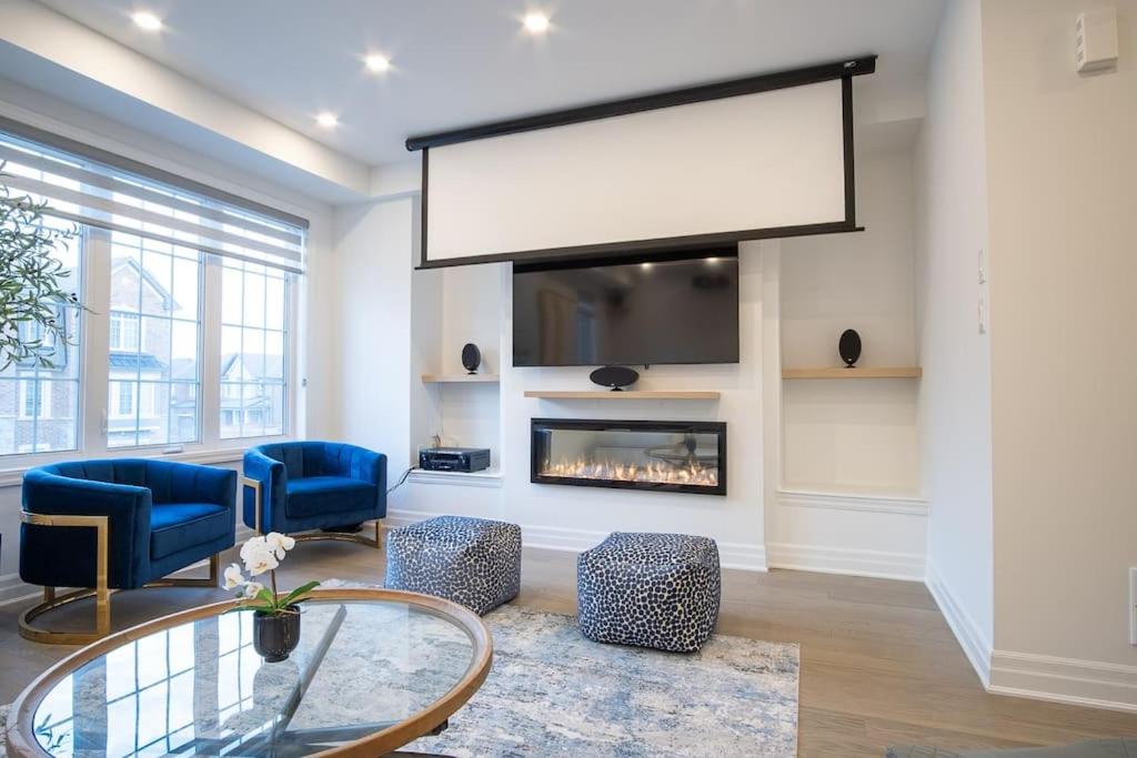 a living room with a fireplace and blue chairs at Modern 4-Bed Townhome with Cinema & Roof Terrace in Oakville